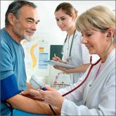 Doctor taking blood pressure of patient while another doctor stands by taking notes