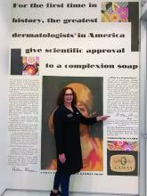 Dr. Leslie S. Baumann in her office, in front of a Camay soap ad from the 1920s.