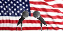 Two microphones against a backdrop of the American flag