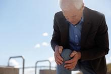 An older man hold his painful knee.