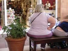 An obese woman sits on a bench