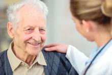 A female doctor comforting an elderly man.