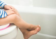 A potty-training toddler sitting on a commode