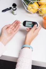 A woman taking a blood glucose montoring test on a device.