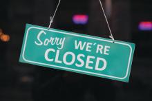 A &quot;sorry we're closed&quot; sign hanging outside of a business.