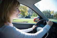 A teenage female driver is shown behind the wheel of a car.