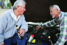 Two Hispanic men not involved in the study work on a car.