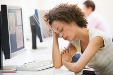 A young woman is shown sleeping in front of computer