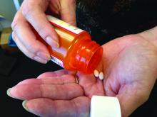 Woman with pill bottle, shaking pills into her hand.