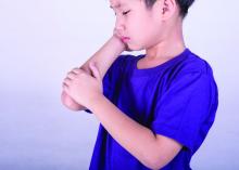 Young boy in pain holding his elbow