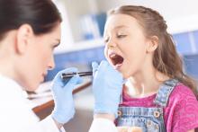 A health care provider checks a child's throat.