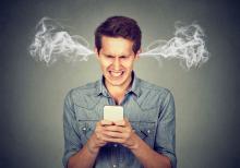 Angry man reading a text message on his smartphone blowing steam coming out of his ears