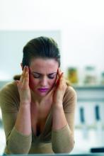 A woman holds her fingers to the sides of her head during a migraine attack.