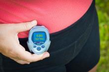 A woman checks the pedometer at her waist.