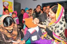 Indo-pakistani women are shown administered polio vaccines to children.