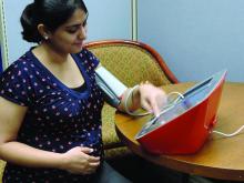 A pregnant woman uses a blood pressure monitor.