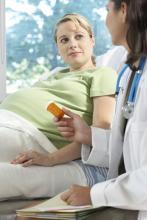 Female doctor giving a bottle of pills to a pregnant woman