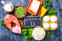 Vitamin D written on a blackboard surrounded by vitamin D dense foods.