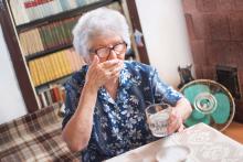 An elderly woman takes pills